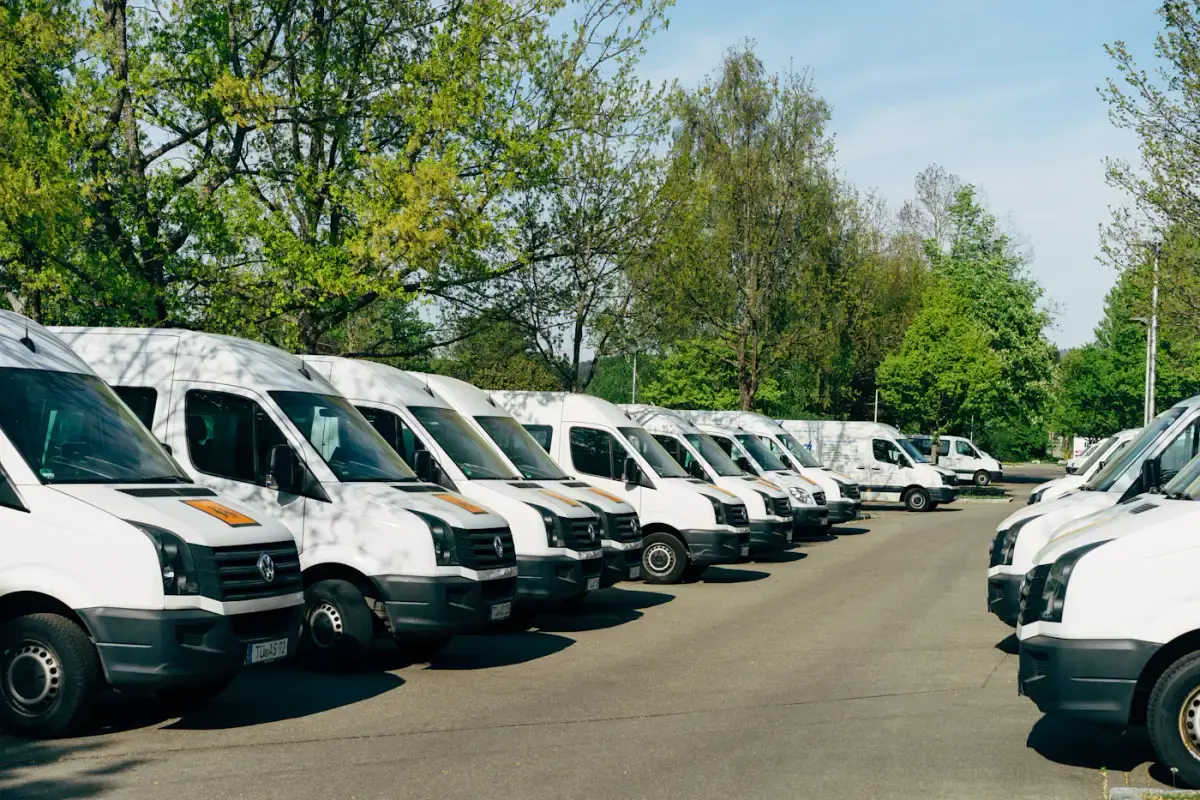 Une flotte d'utilitaires blancs identiques alignés sur le parking d'une entreprise.